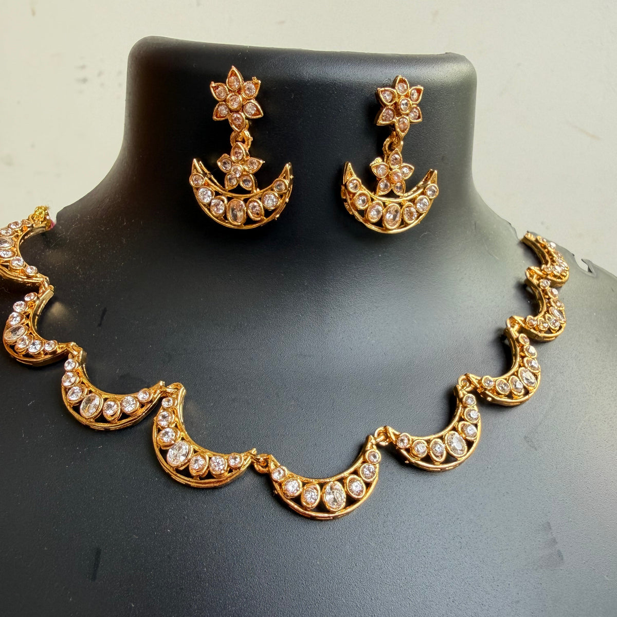 Gold crescent moon and star jewelry set with rhinestone embellishments, displayed on a black mannequin bust.